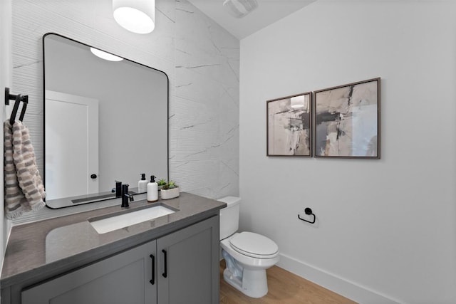 bathroom with toilet, baseboards, wood finished floors, and vanity