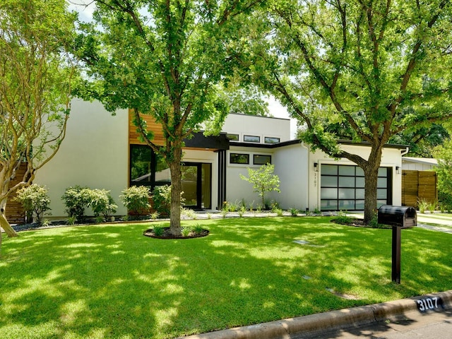 view of front facade with a garage, a front yard, and stucco siding