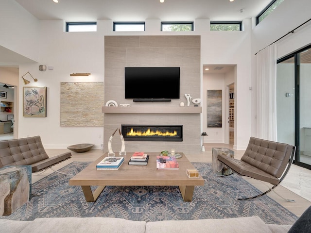 living room with a towering ceiling, plenty of natural light, baseboards, and a tiled fireplace