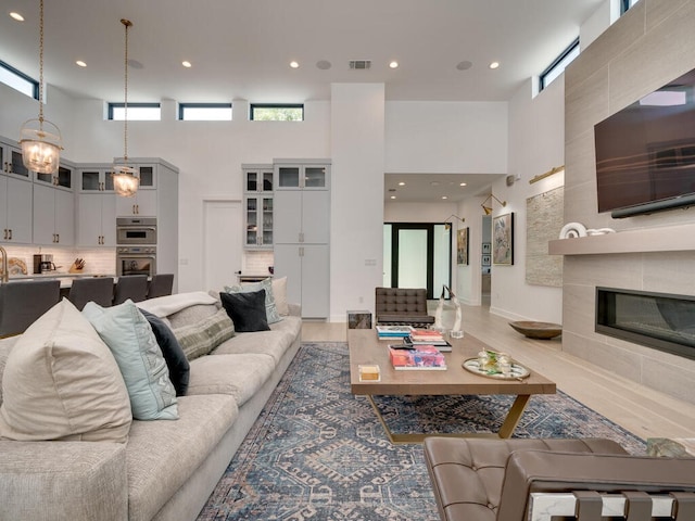 living room featuring recessed lighting, visible vents, a fireplace, and a high ceiling