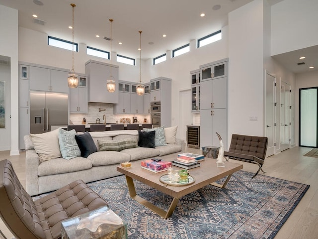 living room featuring light wood-type flooring, baseboards, wine cooler, and visible vents