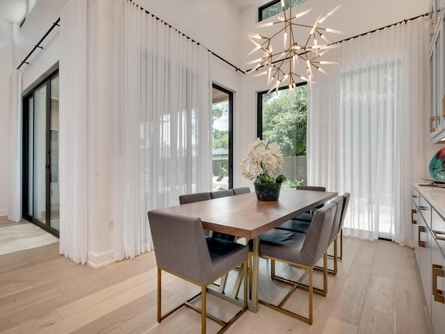 dining space with a chandelier, a towering ceiling, and light wood-style flooring