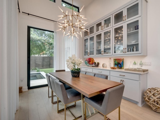 dining space with light wood-type flooring and an inviting chandelier