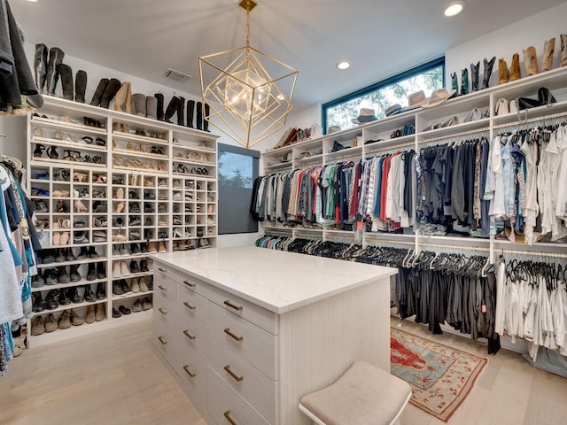 spacious closet with light wood-style floors, visible vents, and a chandelier