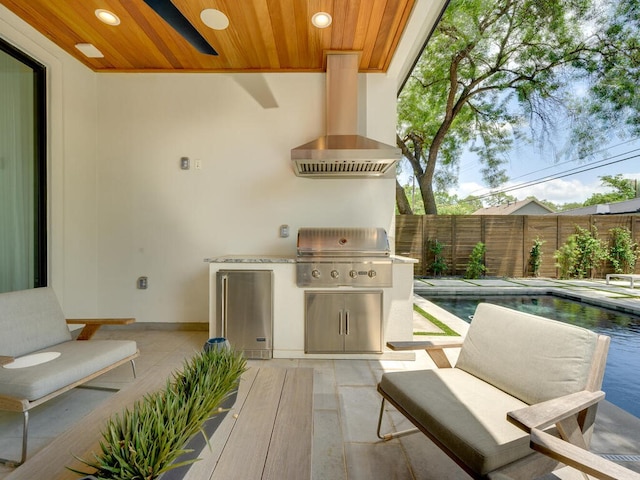 view of patio / terrace featuring exterior kitchen, grilling area, fence, and a fenced in pool