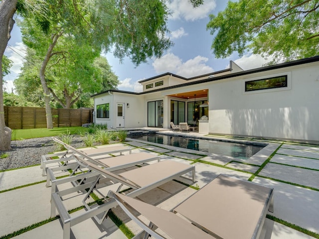 rear view of property with an outdoor pool, stucco siding, a patio, and fence