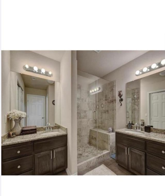 bathroom with a stall shower, two vanities, and a sink