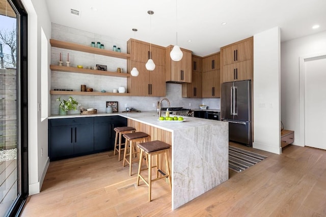 kitchen featuring high quality fridge, a peninsula, light wood-type flooring, a kitchen bar, and open shelves