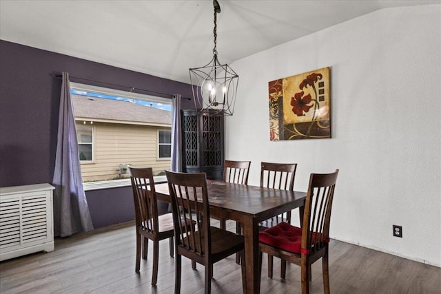 dining space with visible vents, vaulted ceiling, and wood finished floors