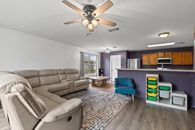 living area with dark wood finished floors, visible vents, and a ceiling fan