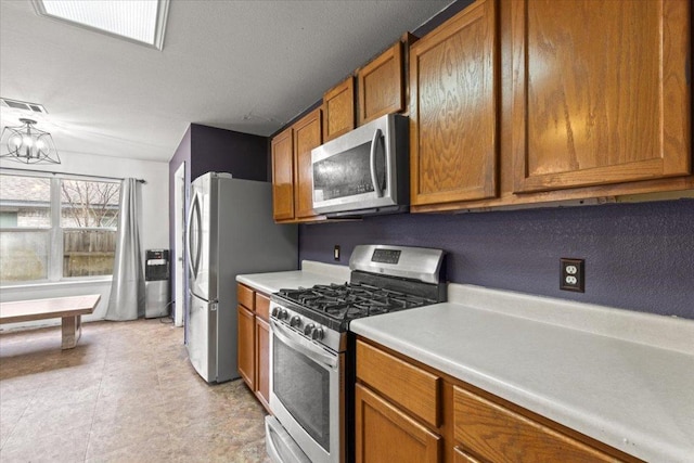 kitchen featuring visible vents, light countertops, appliances with stainless steel finishes, brown cabinetry, and an inviting chandelier