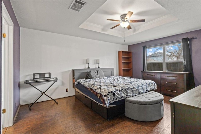 bedroom featuring visible vents, a tray ceiling, dark wood-type flooring, and ornamental molding