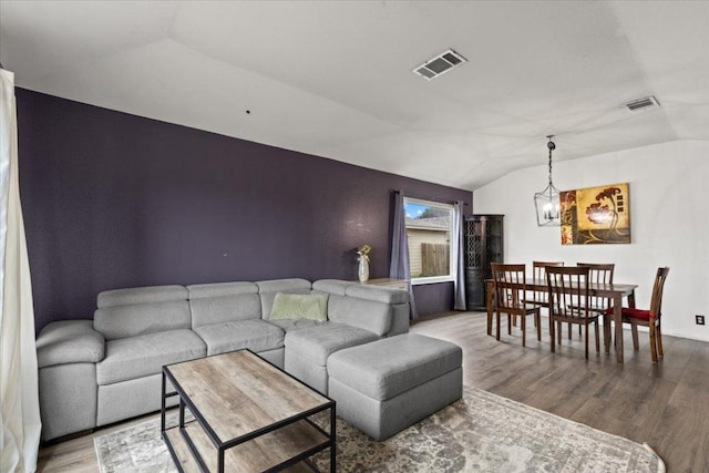 living area featuring lofted ceiling, visible vents, and wood finished floors