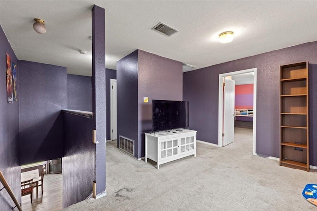 carpeted living room with baseboards, visible vents, and a textured wall