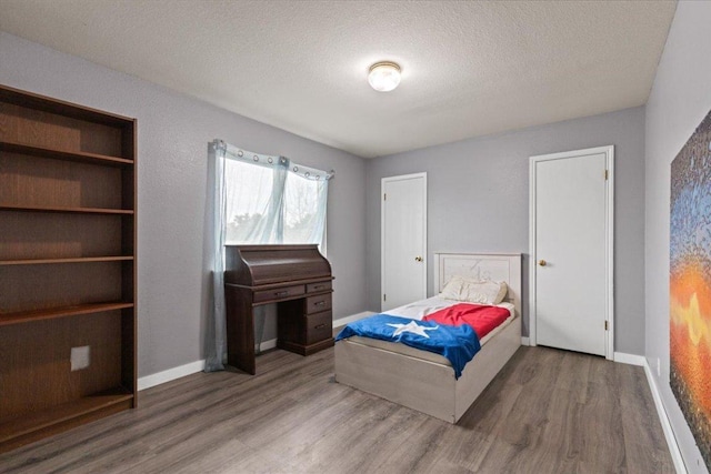 bedroom featuring a textured ceiling, wood finished floors, and baseboards