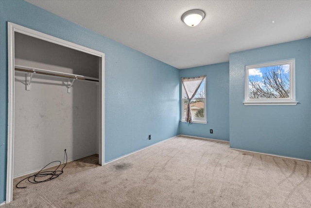 unfurnished bedroom featuring a textured ceiling, a closet, and carpet flooring