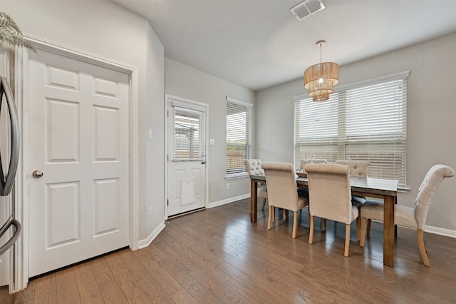 dining space with a notable chandelier, wood finished floors, visible vents, and baseboards