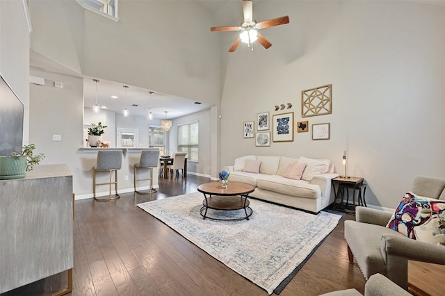 living room featuring ceiling fan, baseboards, and dark wood-type flooring