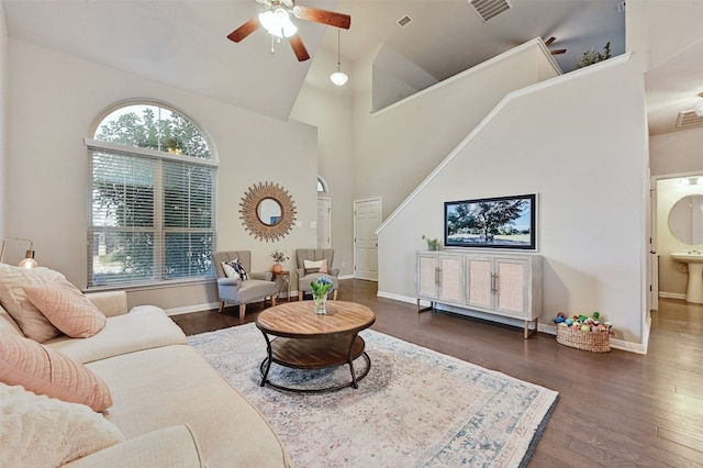 living room featuring visible vents, baseboards, a ceiling fan, wood finished floors, and high vaulted ceiling