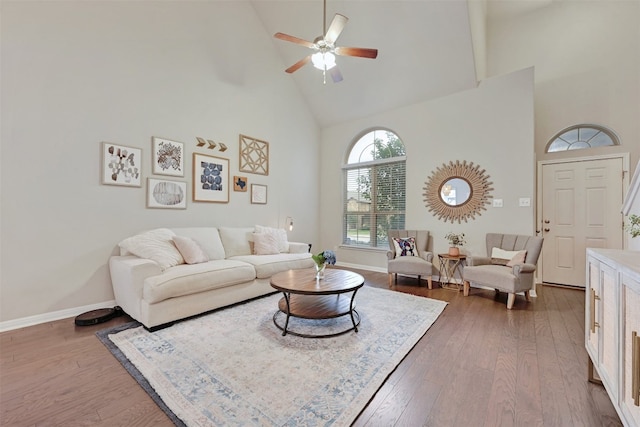 living room with high vaulted ceiling, hardwood / wood-style flooring, baseboards, and a ceiling fan