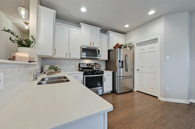 kitchen with tasteful backsplash, dark wood finished floors, appliances with stainless steel finishes, light countertops, and a sink