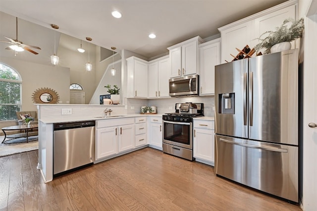 kitchen featuring light wood finished floors, stainless steel appliances, light countertops, decorative backsplash, and a sink