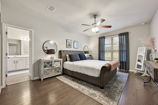 bedroom featuring dark wood-style flooring, a ceiling fan, visible vents, baseboards, and ensuite bath