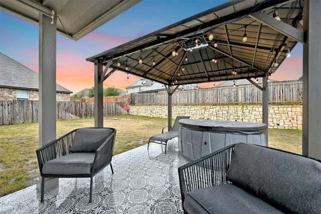 patio terrace at dusk featuring a gazebo, a lawn, and a fenced backyard