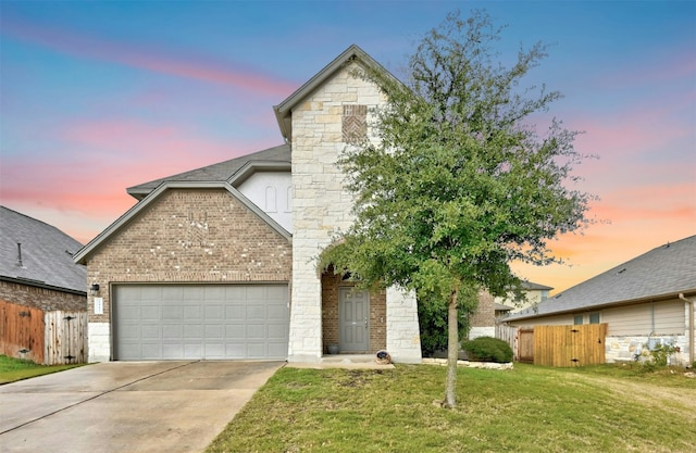 traditional-style home featuring concrete driveway, an attached garage, fence, a front lawn, and brick siding