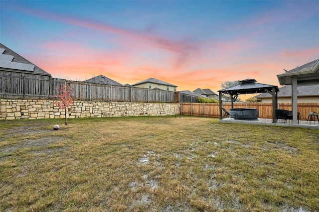 yard at dusk with a patio area, a fenced backyard, and a gazebo