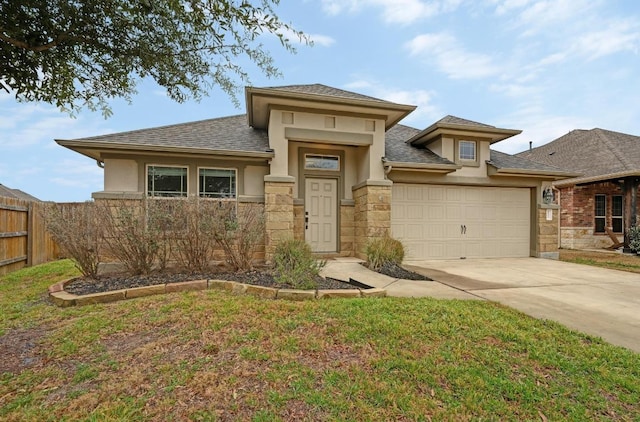 prairie-style home with stucco siding, concrete driveway, an attached garage, fence, and stone siding