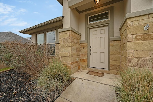 view of exterior entry featuring stone siding and stucco siding