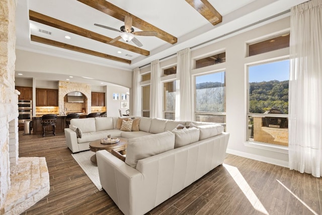 living room with visible vents, arched walkways, dark wood-style flooring, a high ceiling, and beam ceiling