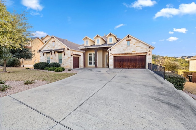 view of front of house with a garage, stone siding, driveway, and fence