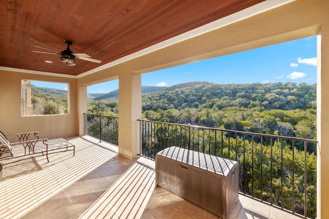 balcony with a ceiling fan, a sunroom, and a wooded view