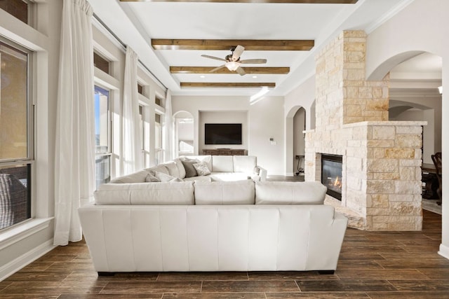 living room with baseboards, a ceiling fan, wood tiled floor, a fireplace, and beam ceiling