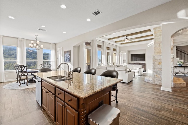 kitchen with visible vents, a sink, a kitchen bar, and wood finished floors