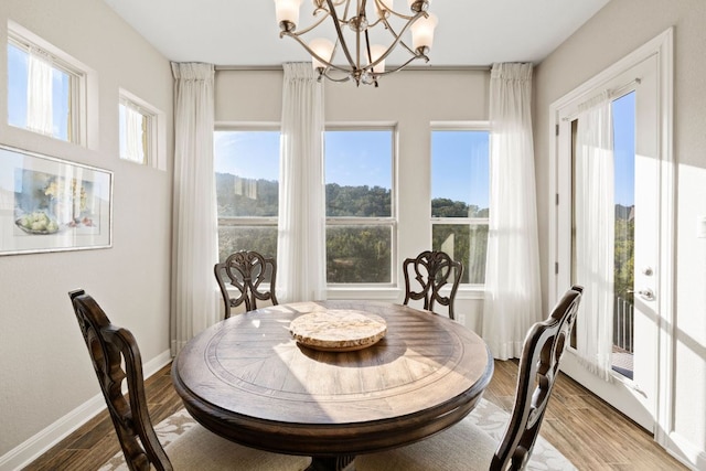 dining space featuring baseboards, a chandelier, and wood finished floors