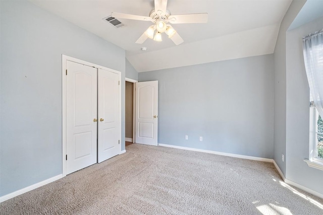 unfurnished bedroom featuring visible vents, baseboards, carpet, and lofted ceiling