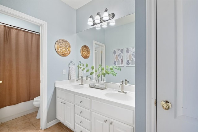 bathroom featuring tile patterned floors, toilet, double vanity, and a sink