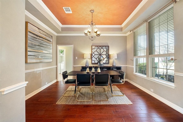 dining area featuring a raised ceiling, an inviting chandelier, hardwood / wood-style floors, and ornamental molding