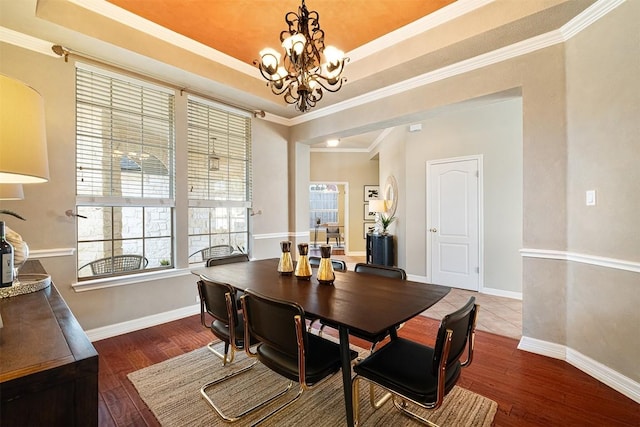 dining area with a raised ceiling, ornamental molding, hardwood / wood-style floors, baseboards, and a chandelier