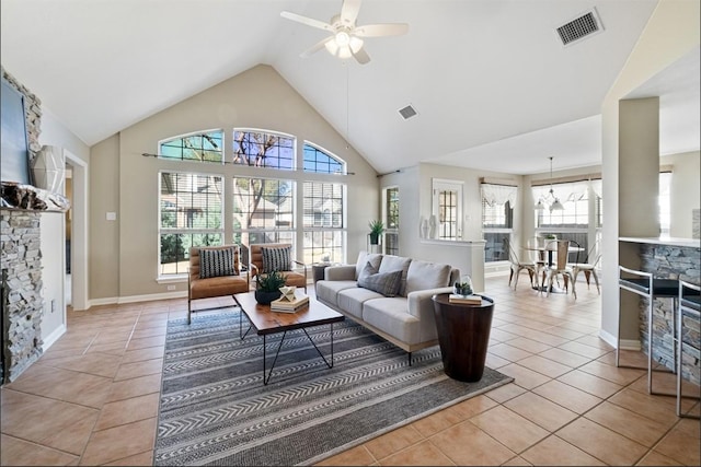 living area with light tile patterned floors, visible vents, high vaulted ceiling, and a stone fireplace