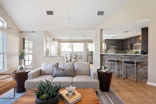 living room with light tile patterned flooring, visible vents, and vaulted ceiling