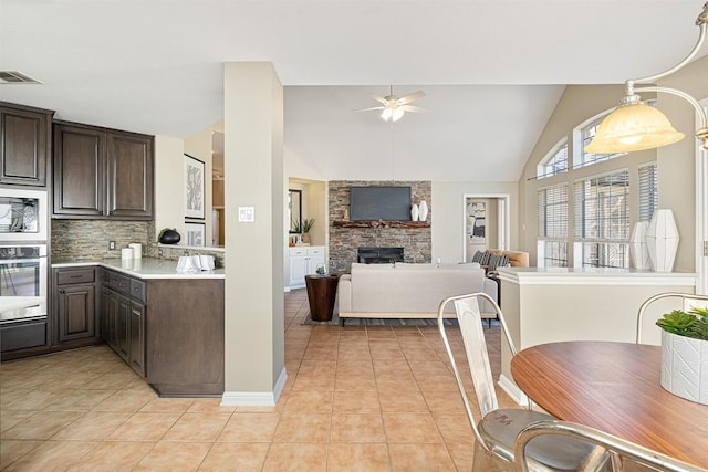 kitchen featuring light tile patterned flooring, a fireplace, appliances with stainless steel finishes, and dark brown cabinets