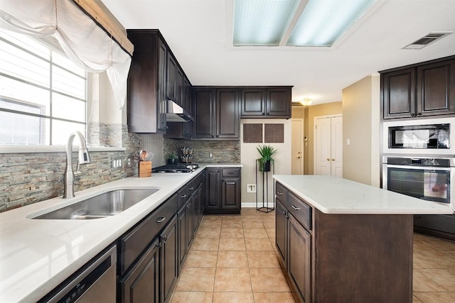 kitchen with visible vents, a sink, under cabinet range hood, tasteful backsplash, and stainless steel appliances