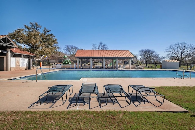 community pool featuring a gazebo, a patio area, fence, and an outbuilding