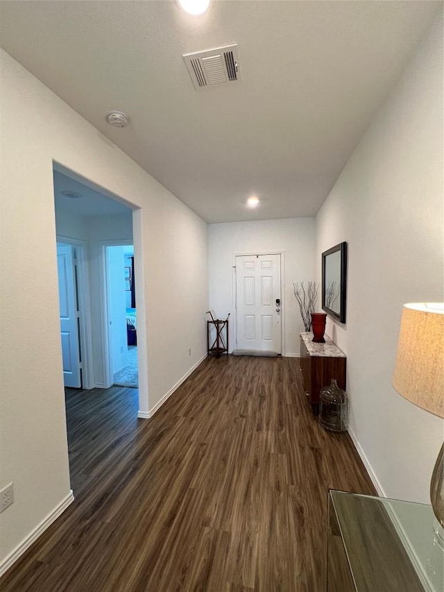 corridor featuring dark wood finished floors, visible vents, and baseboards