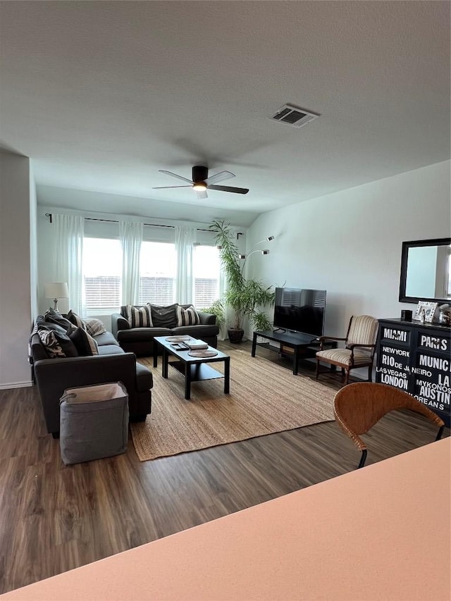 living room featuring wood finished floors, visible vents, and a ceiling fan