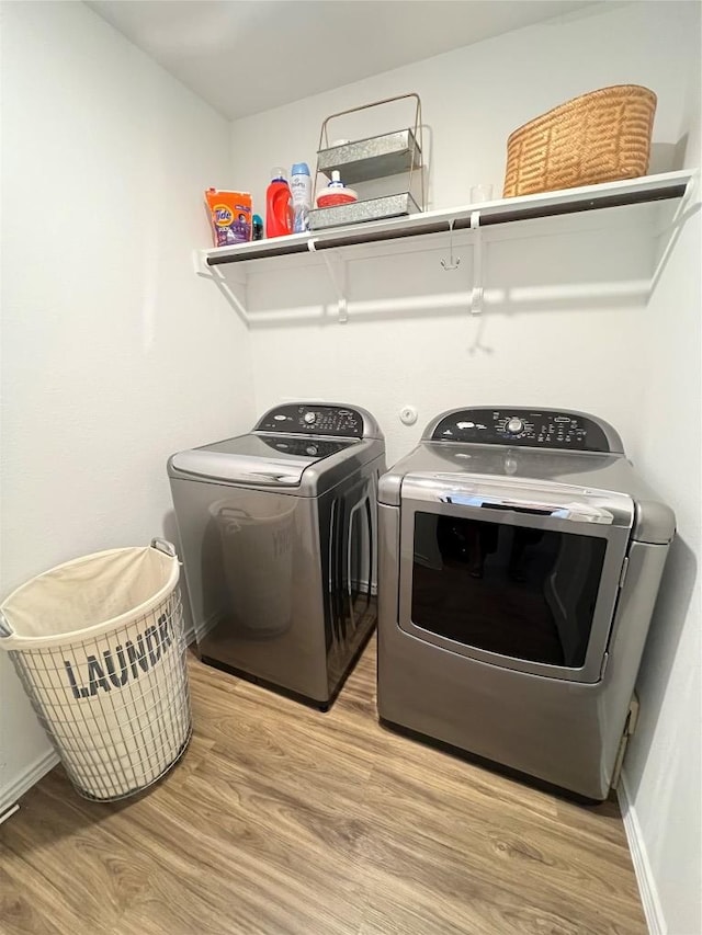 laundry room with laundry area, washing machine and clothes dryer, light wood-style flooring, and baseboards